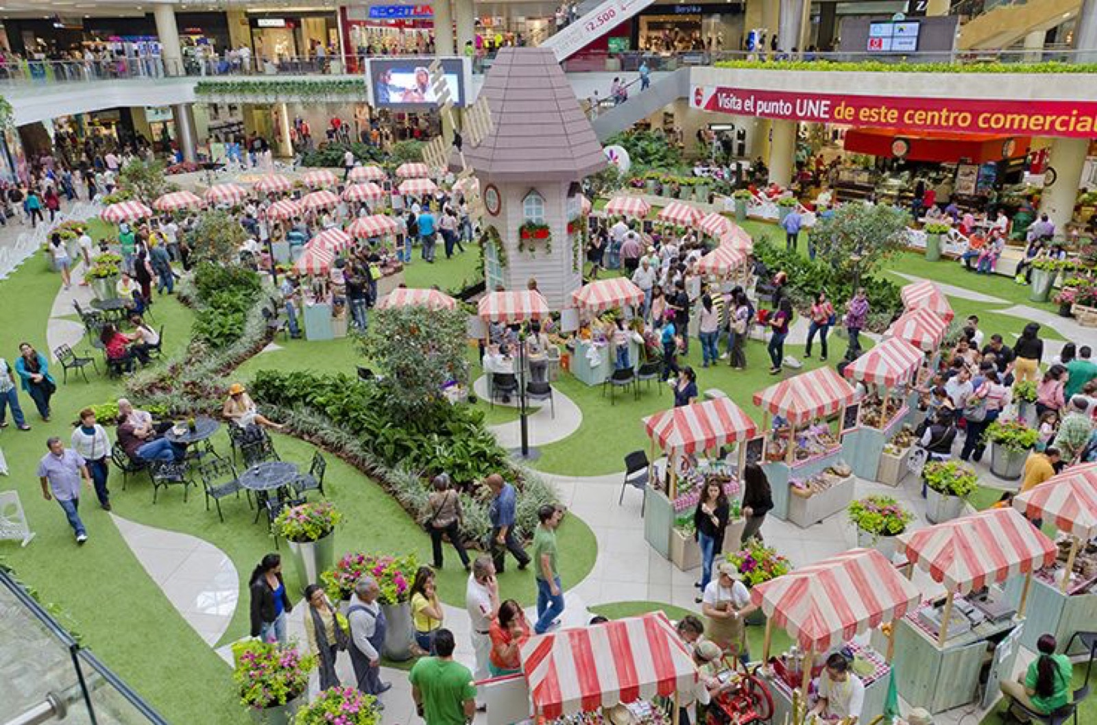 Feria de emprendedores con toldos a rayas dentro de un centro comercial